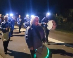 La fanfare en tête du cortège, tambours illuminés.